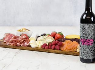 Three bottles of William Wright limited edition reserve wine collection including Chardonnay, Cabernet Sauvignon and a Red Wine Blend in front of a charcuterie board.
