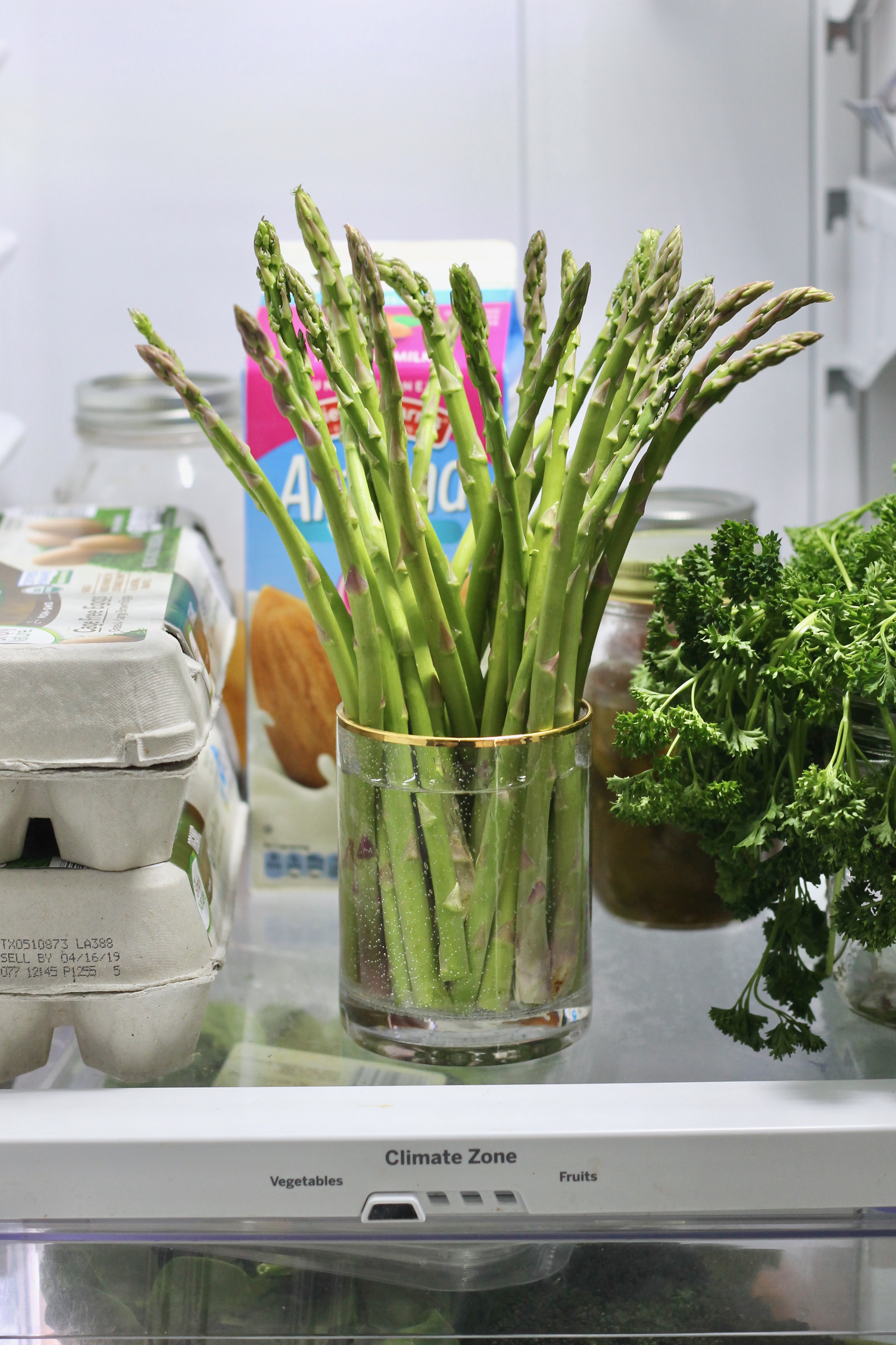 Asparagus placed upwards in a cup or water in a refrigerator